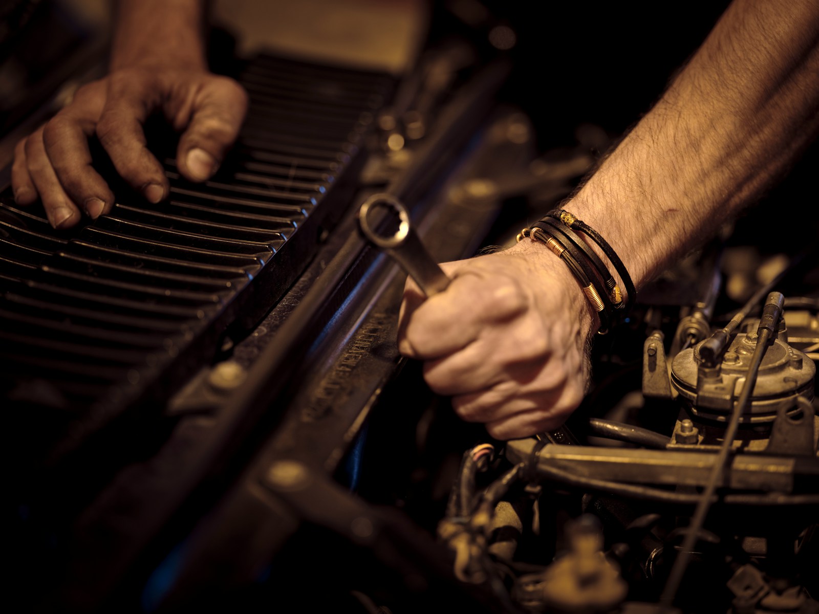 Ruce mechanika pracující klíčem na motoru v dílně